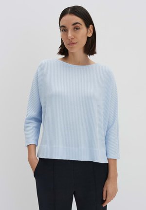 Pull bleu clair, côtelé, avec des manches trois-quarts et un décolleté large. L'ourlet est droit et arrive à la taille.
