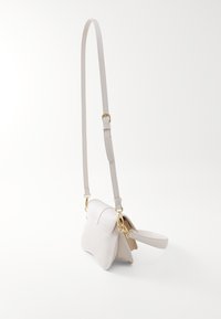 Piccola borsa in pelle bianca con forma arrotondata, tracolla regolabile e dettagli in metallo dorato. Texture liscia e design minimalista.