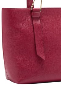 Sac fourre-tout en cuir rouge avec une finition texturée, détail de sangle verticale et quincaillerie dorée. Forme structurée avec un fond plat pour plus de stabilité.