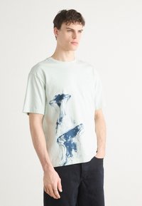 Myntegrønn bomulls T-skjorte med en marineblå manet grafikktrykk. Enkel båtformet hals og korte ermer, avslappet passform.