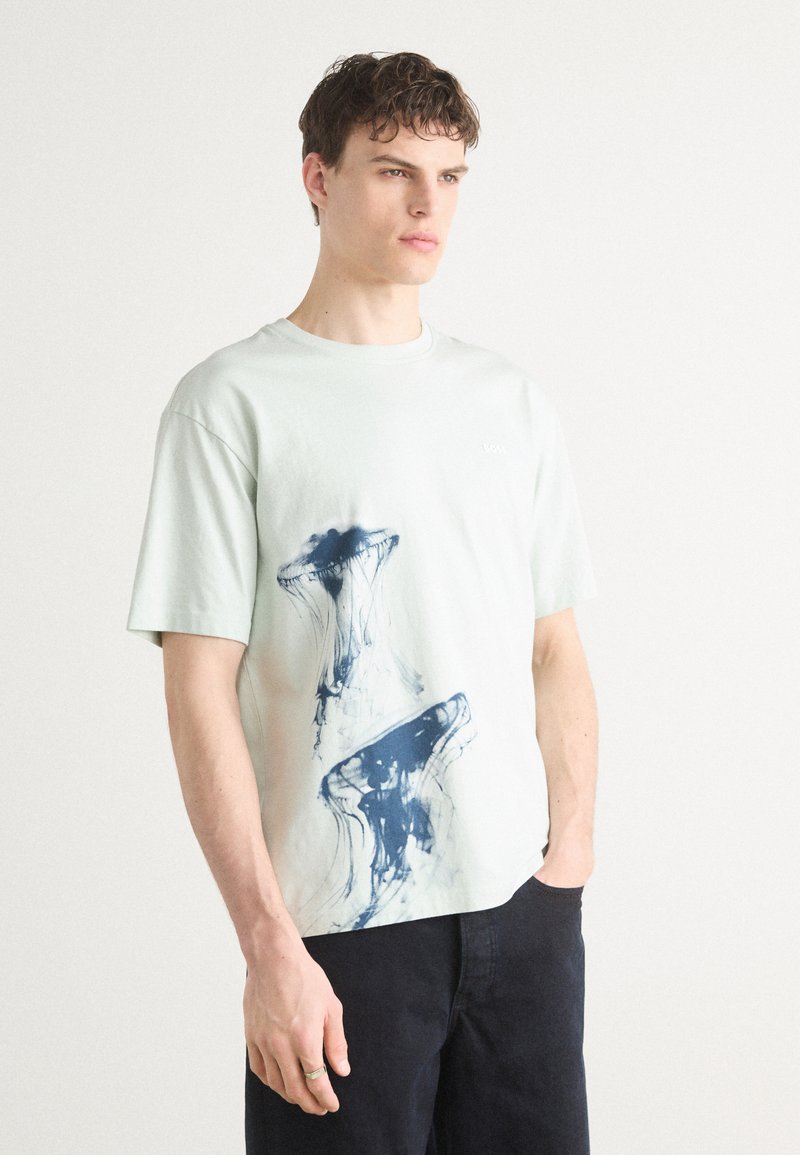 Myntegrønn bomulls T-skjorte med en marineblå manet grafikktrykk. Enkel båtformet hals og korte ermer, avslappet passform.