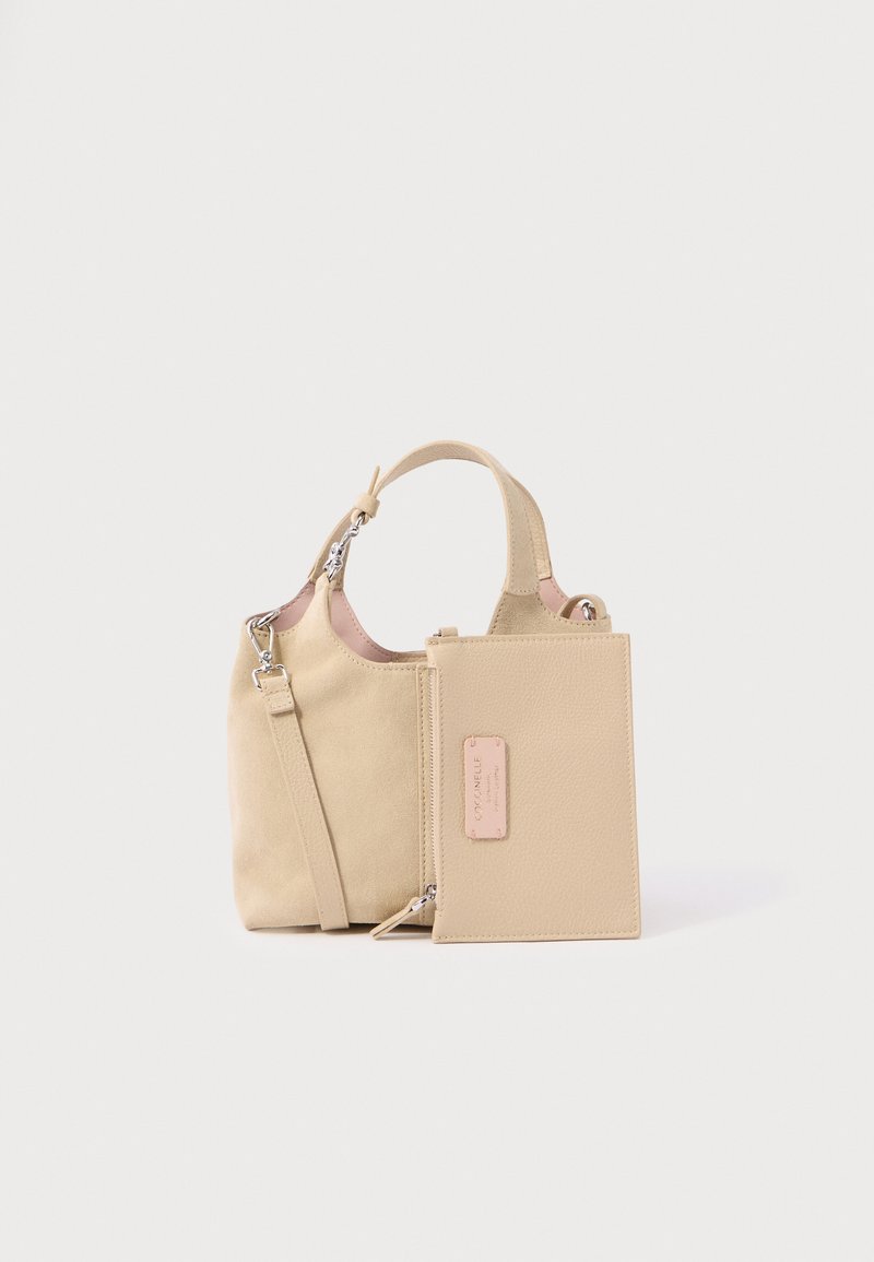 Sac à main en daim beige avec un corps structuré, des poignées courtes et une pochette zippée détachable. Comprend un accent rose sur l’étiquette de la pochette.