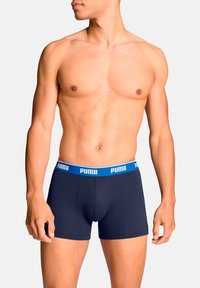 Boxer-shorts bleu marine foncé avec une taille élastique bleue présentant le logo "PUMA" en blanc. Texture lisse, design ajusté, conçu pour le confort.
