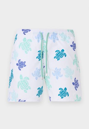 White swim shorts with turquoise, blue, and navy turtle patterns and a green drawstring waist on a plain background.
