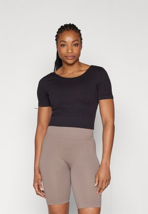Svart rillet kortermet crop-top kombinert med beige rillet high-waisted sykkelshorts. Glatt stoff med en tætsittende design.