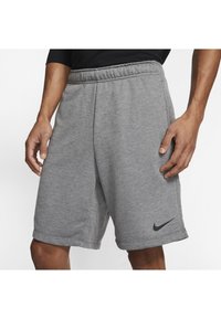 Grijze sportshorts van zacht materiaal met een elastische tailleband. Heeft een zwart Nike-logo op de linker zoom.