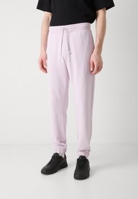 Lys rosa sweatpants med elastisk talje og snor, der har ribbede manchetter og et præget logo-detajle på hoften.