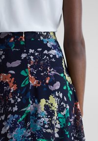 Marinblå blommig kjol med ett livligt mönster i orange, gröna och lila nyanser; tyget har en mjuk textur och ett figursytt midjeband.