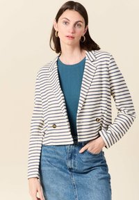 Blazer a righe corto in crema e blu navy, caratterizzato da un design doppiopetto, revers a punta e bottoni dorati. Indossato sopra un top color teal.