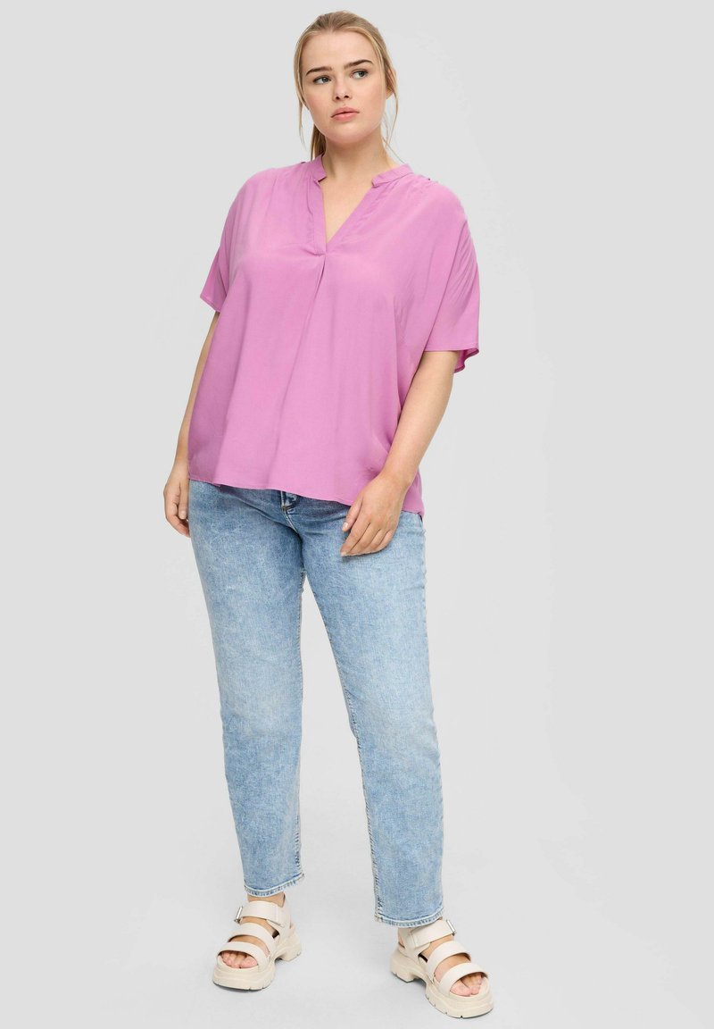 Roze, mouwloze blouse met een v-hals, gemaakt van een gladde stof. Draag hem met lichtblauwe jeans en beige sandalen. Eenvoudig ontwerp, comfortabele pasvorm.