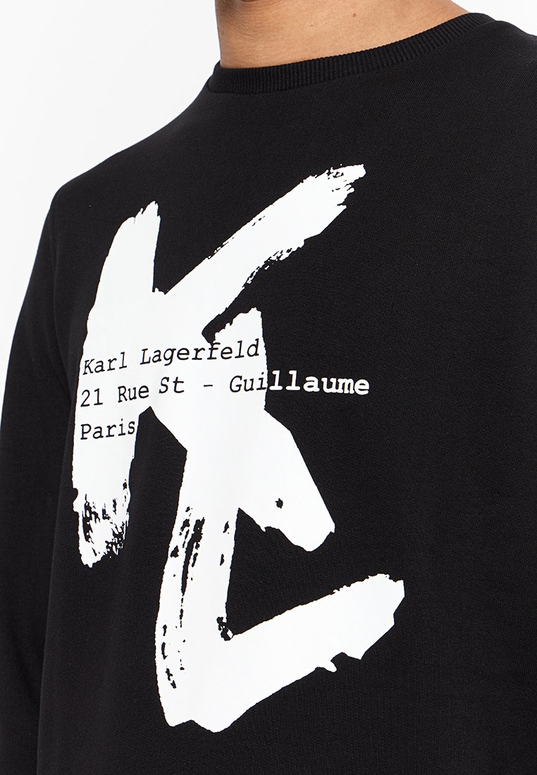 Sudadera negra con un gran gráfico blanco de las letras "K" y "L." El texto dice "Karl Lagerfeld 21 Rue St - Guillaume París."