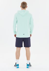 Mintgrøn langærmet hættejakke med hætte, parret med navy shorts. Funktioner inkluderer en slim fit og logo detalje på bagsiden.
