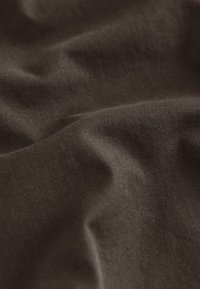 Dark brown fabric with a smooth texture, featuring subtle creases and folds, indicating softness and drape.