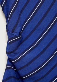 Tessuto blu con righe verticali in blu scuro e bianco, caratterizzato da una consistenza morbida e una leggera caduta, che mette in mostra un design informale.