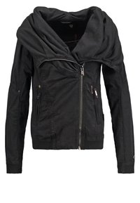 Veste noire cintrée avec grand col plié, fermeture éclair asymétrique à l'avant et poches zippées de chaque côté.