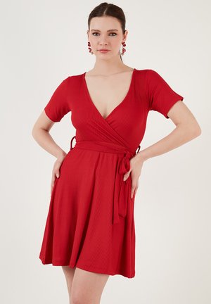 Red, ribbed wrap dress with short sleeves, deep V-neck, and tie closure at the waist. Flared skirt reaches mid-thigh, smooth texture.