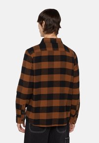Brun og sort ternet flannel skjorte med lige skæring, knapmanchetter og klassisk krave, lavet af blødt, tekstureret stof.
