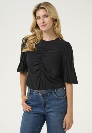 Schwarzes Oberteil mit Puffärmeln und gerafftem Vorderteil, kombiniert mit blauen Jeans. Glatte Stoffoberfläche mit rundem Ausschnitt und lockerer Passform.