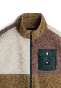 Giacca in pile con colletto alto nei colori crema, marrone e beige. Presenta una tasca a toppa verde, cuciture a contrasto e chiusura zip.