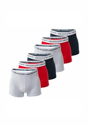 Ensemble de cinq slips de bain présentant un mélange de couleurs blanches, rouges et bleues marines, avec une taille logo GANT et un tissu lisse et extensible.