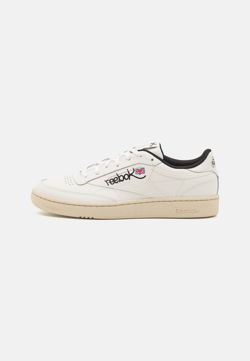 Basket basse blanche Reebok avec semelle crème, intérieur noir et logo Union Jack sur le côté, présentée sur un fond blanc uni.