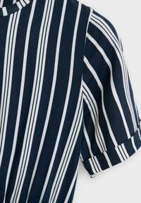 Tmavě modrá košile s krátkým rukávem, bílými vertikálními pruhy a ohrnutými manžetami.