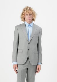 Light gray suit with a tailored design, featuring a single-breasted jacket and flat-front trousers. Underneath, a light blue collared shirt.