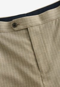 Pantaloni din stofă bej cu un model cu dungi, având o talie bleu închis, închidere cu nasture și un design frontal plat.