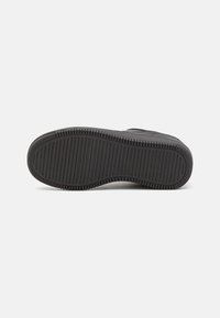 Suola di scarpa in gomma nera con modelli di impugnatura texturizzati. Il design presenta rilievi orizzontali e verticali per una migliore aderenza. Bordo liscio, senza marchi visibili.