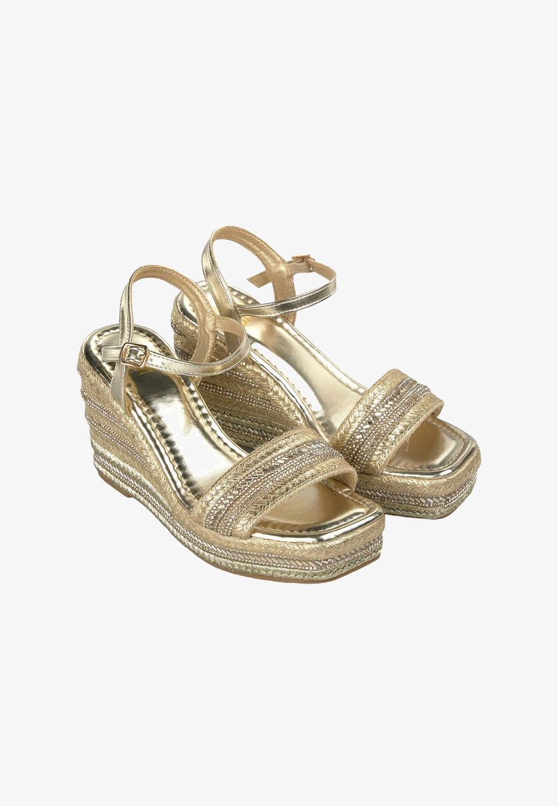 Le sandali wedge in oro presentano cinturini metallici, una piattaforma intrecciata texturizzata e una cinghia attorno alla caviglia. Il design è aperto sulla punta.