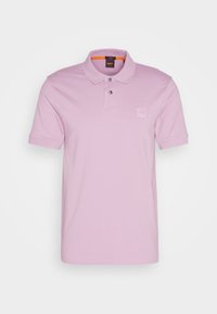 Polo léger rose en coton. Doté d'un col, d'une patte de boutonnage à deux boutons et d'un petit logo sur la poitrine gauche.