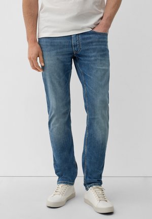 Herren hellblaue taillierte Jeans mit Waschungen, fünf Taschen und einem Standard-Schnitt, kombiniert mit weißen Sneakers.