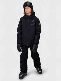 Παιδί ντυμένο με μαύρη σκι jackets, παντελόνια, γάντια, μποτάκια και γυαλιά προστασίας στο κεφάλι, που στέκεται μπροστά σε ένα απλό ανοιχτό φόντο.