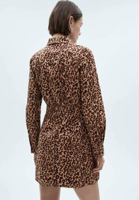 Košeľové šaty s leopardím vzorom v hnedej a pieskovej farbe, s dlhými rukávmi, sťahovacím pásom a golierom pre štruktúrovaný siluetu.