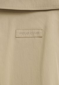 Beige fabric with a stitched rectangular label reading "POLO CLUBE" centered below a horizontal seam.