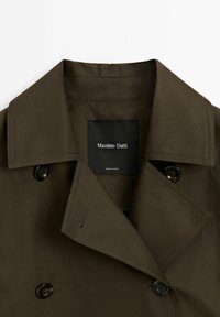 Manteau vert olive foncé croisé avec large col et boutons noirs, étiquette Massimo Dutti à l’intérieur de l’encolure.