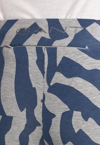 Pantaloni corti blu e grigi con un motivo e una texture liscia. Presentano una vita elastica con il logo "GANT" e un design astratto.