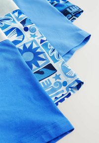 Kortärmad skjorta i ljusblå bomull med grafiskt mönstrade ärmar i olika blå nyanser, som har geometriska och abstrakta designer.