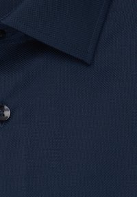 Polo shirt navy in tessuto con una trama testurizzata, dotato di colletto e un bottone scuro. Il materiale sembra traspirante, adatto per un abbigliamento casual.