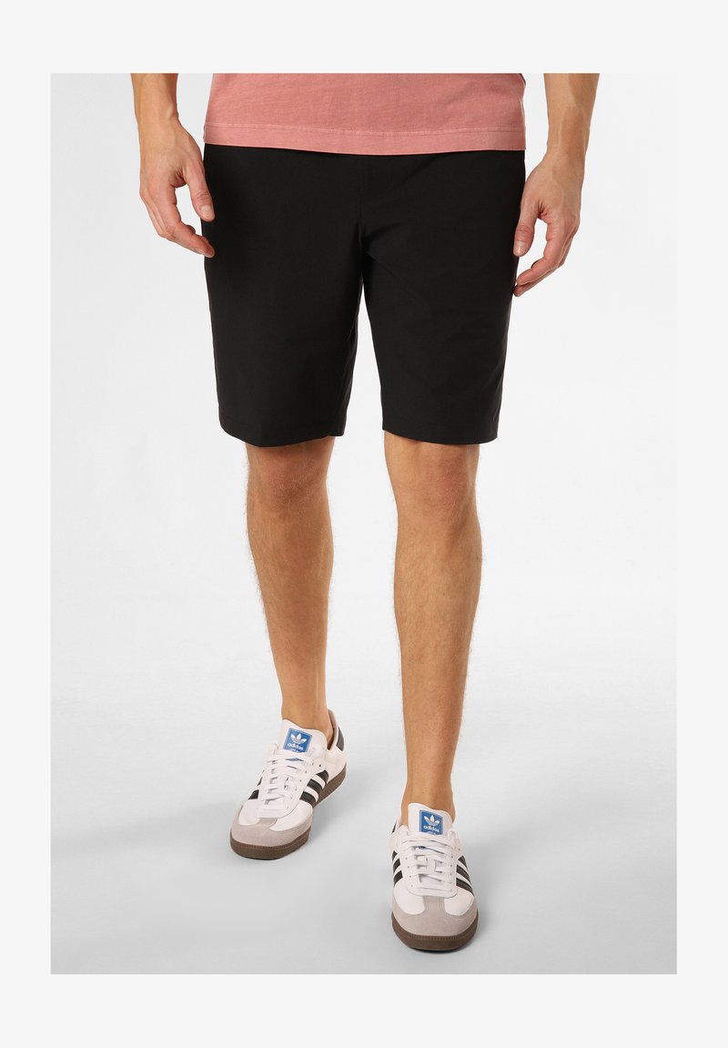 Mustad lühikesed püksid sirge jala disainiga, siledast materjalist ja ilma nähtavate mustriteta, koos tumedate aktsentidega valgete tossudega.