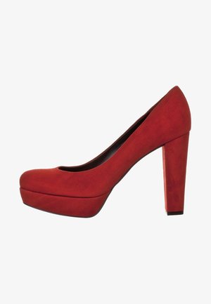 Escarpin rouge en suede à talons hauts avec un bout rond, une semelle plateforme et un talon épais, mettant en valeur une texture lisse et une couleur uniforme.