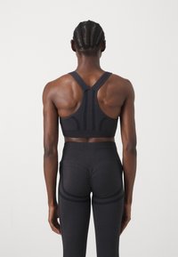 Sujetador deportivo negro con diseño de espaldar en u, que presenta paneles texturizados. Leggings negros ajustados con costuras de acento y una cintura alta.