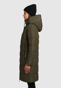 Pohodlný zelený kabát s kapucňou, bočnými zipsovými vreckami a trojuholníkovou nášivkou. Dizajn má prešívanú textúru a dlhé rukávy.