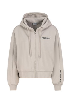 Hellbeige Kapuzenjacke mit Reißverschluss und Kordeln, vorne Text „LOVE & PASSION STUDIO COLLECTION“ und Ärmelschrift „MADE WITH“ plus Herzen.