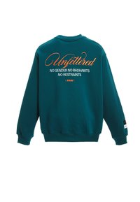 Sudadera verde azulado de manga larga y cuello redondo. En la parte posterior, el texto en naranja y blanco dice "Sin ataduras" y frases adicionales abajo.