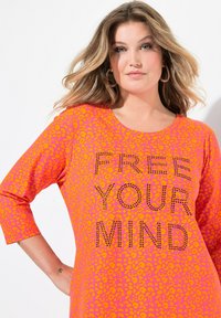 Topp i leopardmönster i rosa och orange med trekvartsärmar och "FRIGÖR DIN SINNE" i rhinstenar fram. Mjuk tyg.
