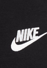 Tessuto nero con logo "NIKE" ricamato in bianco, accompagnato da un design a swoosh. Texture morbida e tipografia semplice e audace.