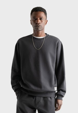 Donkergrijze sweatshirt van zacht katoen, met een geribbelde ronde hals en manchetten, en een klein label op de onderste zoom.