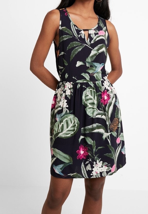 Blommig klänning med en mörk marin bakgrund, som har vita och rosa blommor, gröna blad och ett nyckelhålsdetalj vid halsringningen.