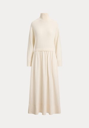 Robe crème à manches longues, avec un col montant côtelé, un corsage en maille ajusté et une jupe fluide longueur cheville, présentée sur un mannequin.